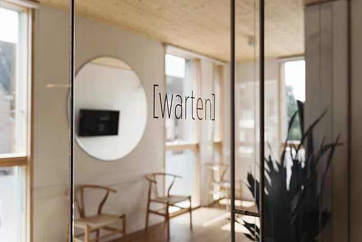 Wartebereich hinter der Glastür mit der Aufschrift warten